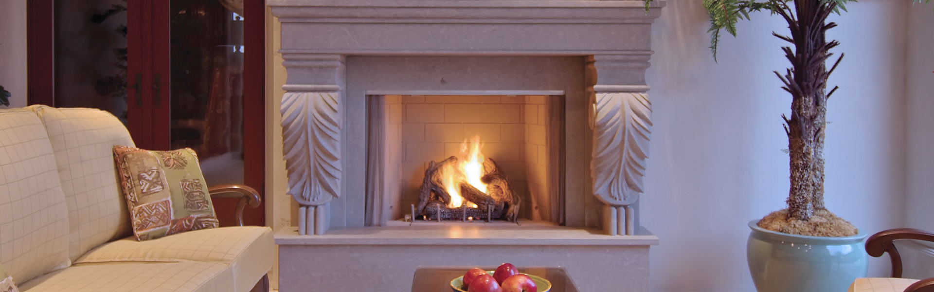 Superior VRE4300 vent-free outdoor gas fireplace with formal mantel surround, palm tree, and outdoor armchair